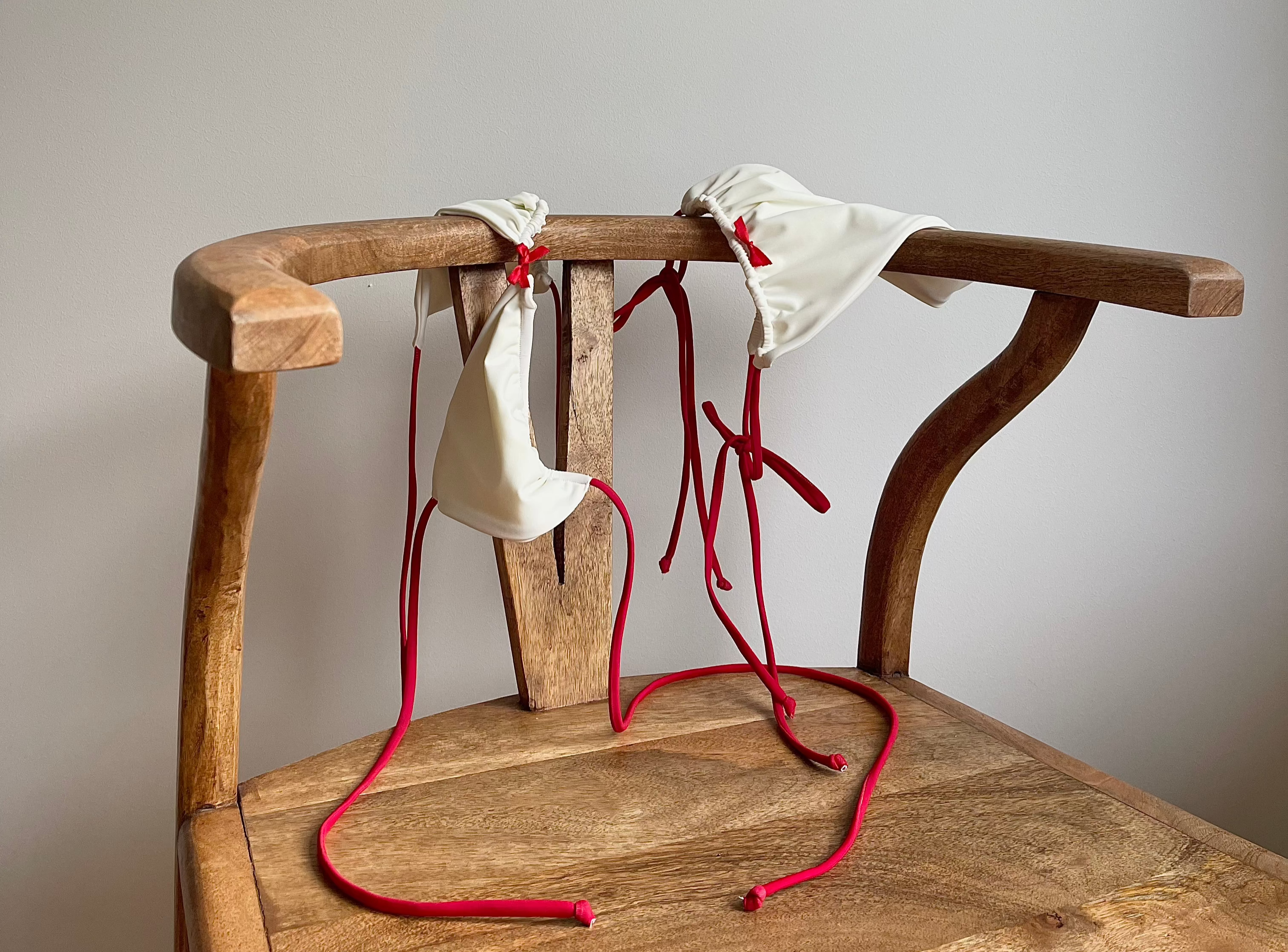 Red and white bikini with bows hanging on a chair 